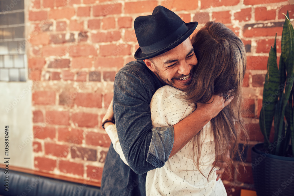 Young man hugging a woman in a coffee shop