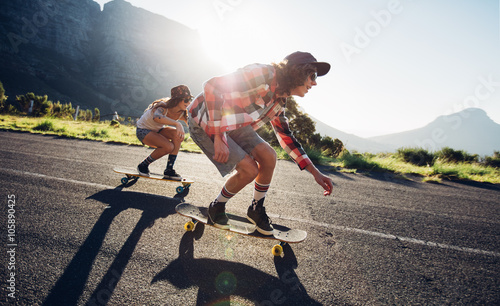 Young friends longboarding down the road photo