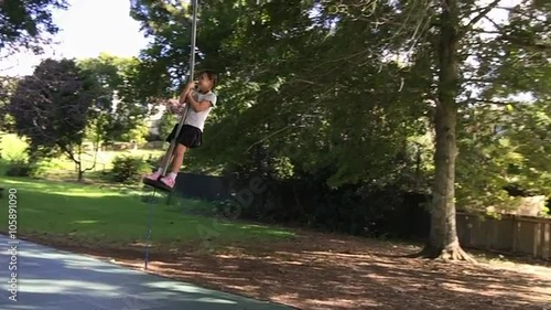 Slow motion child girl (age 05 - 06) rids on Flying Fox play equipment in a children's playground. photo