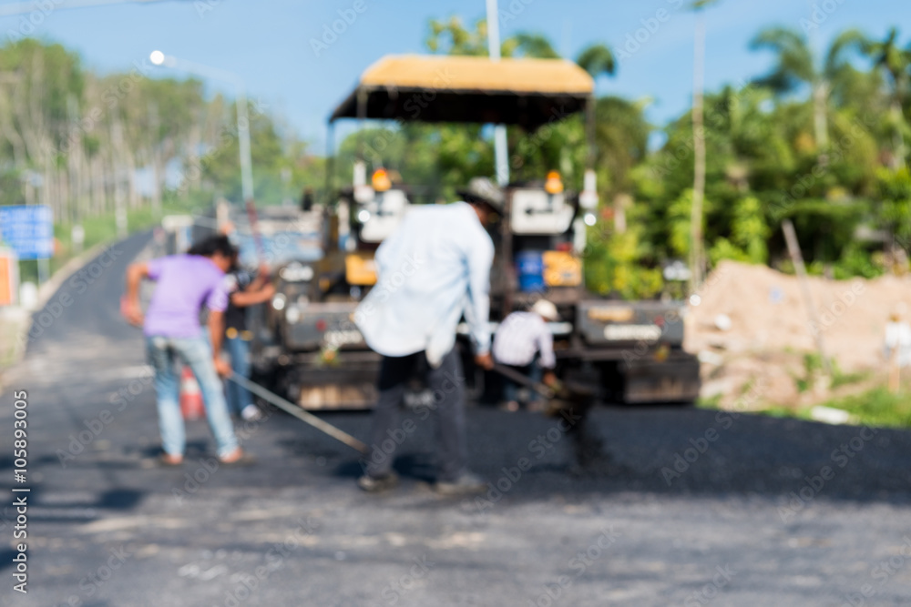 Obraz premium Worker operating asphalt paver machine during road construction