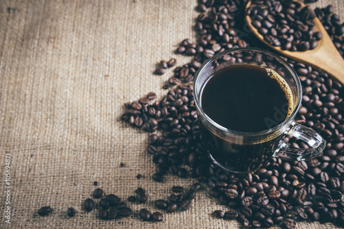 glass cup of espresso coffee with coffee bean on traditional sack textile. Vintage retouching. photo