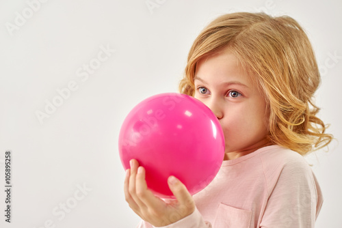 Little girl inflates pink balloon