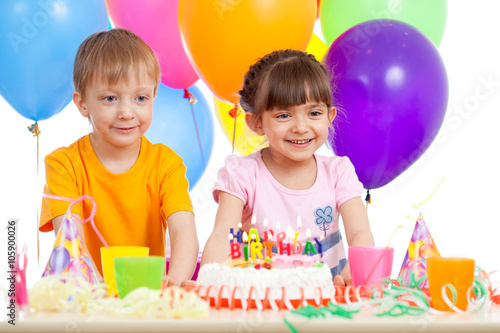 Smiling little boy and girl with birthday cake and color ballons