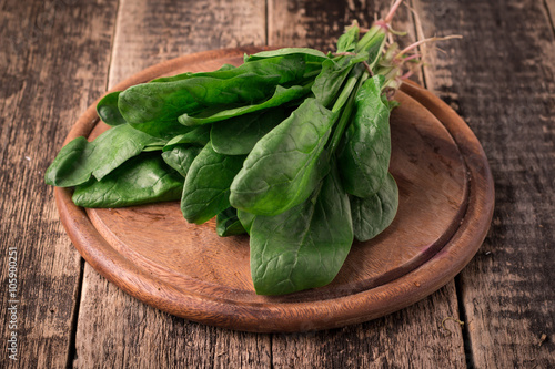 Bunch of fresh spinach with roots over old wooden surface. Dark rustic style