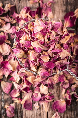 rose petals and dried flowers in spoon on old wooden table