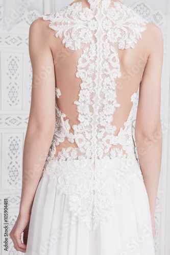 Gorgeous lace dress on a beautiful slim bride. Tanned skin, white lace, translucent fabric. Body parts, torso.