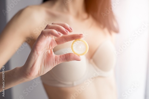 Woman in underwear is holding a condom for a safe sex.