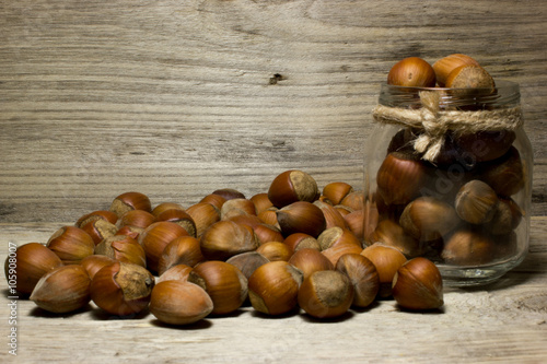 Hazelnut in shell in glass jar on wooden background