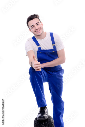 handsome young mechanic holding a tire isolated on white background