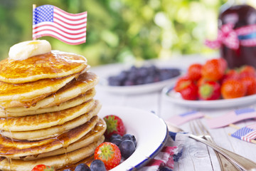 Stack of pancakes with fresh fruit, syrup and butter