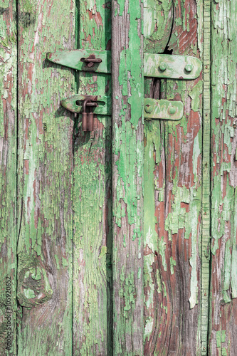 Wooden door with pealing paint and rusty hinges