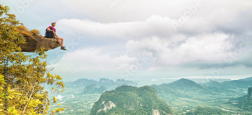 Freedom traveler man sitting and enjoying a beautiful nature from top of mountain. Banner