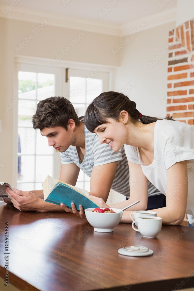Young couple reading book while having breakfast Young couple reading book while having breakfast