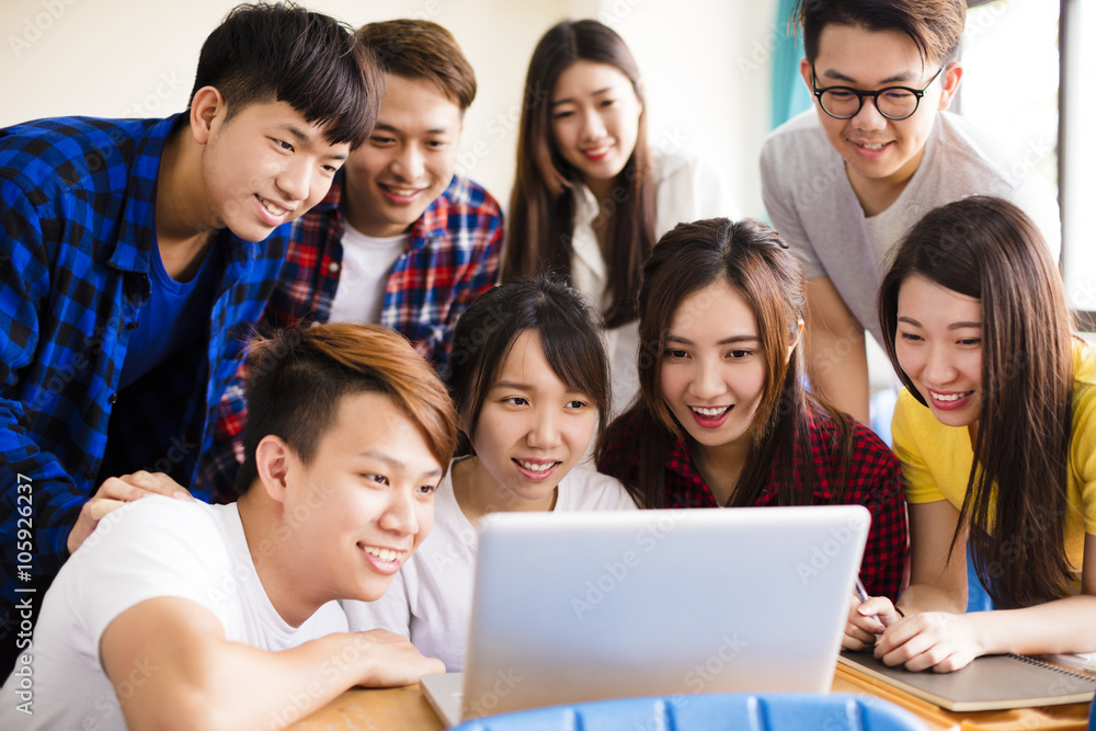 Group of college students watching laptop in classroom Group of college students watching laptop in classroom
