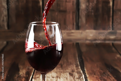 Red wine is pouring from bottle into a glass