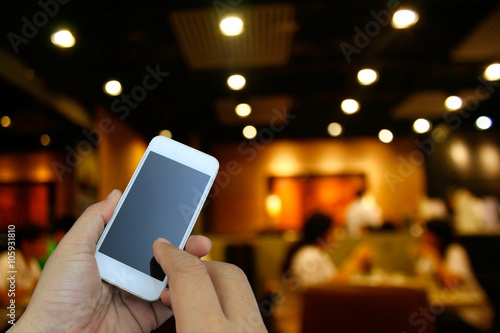 hand holding the smartphone on blur restaurant background