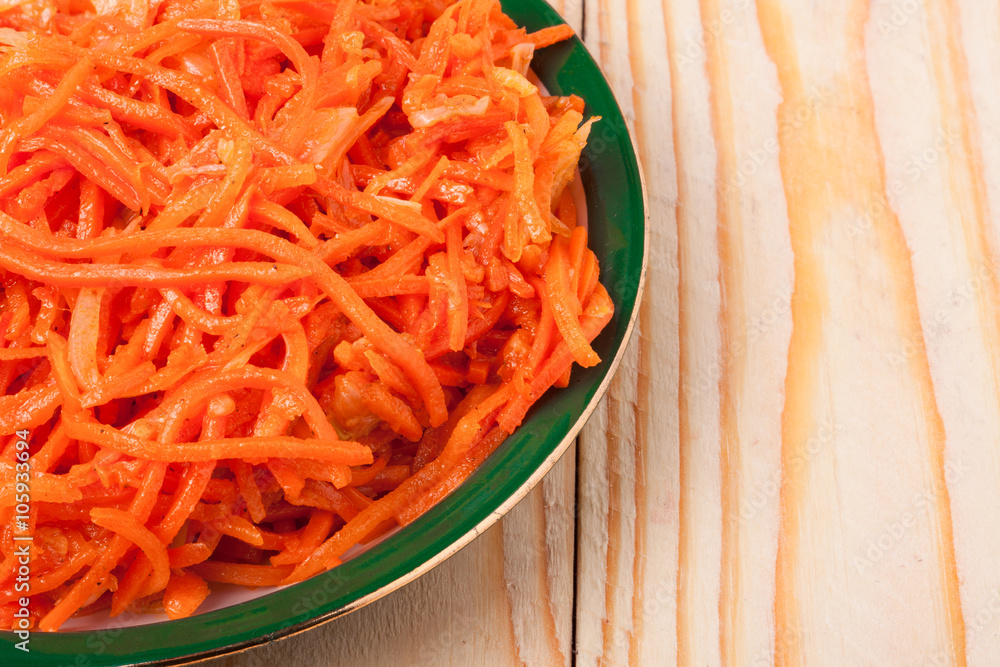 Hot carrot salad in plate on wooden background Hot carrot salad in plate on wooden background