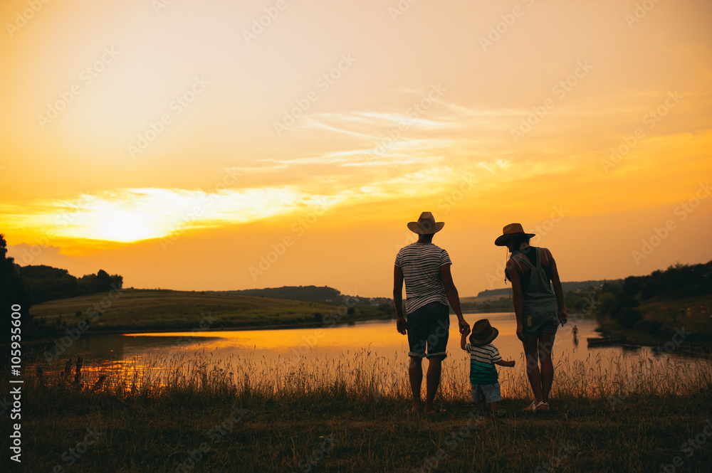 Happy family together, parents with their little child at sunset Happy family together, parents with their little child at sunset