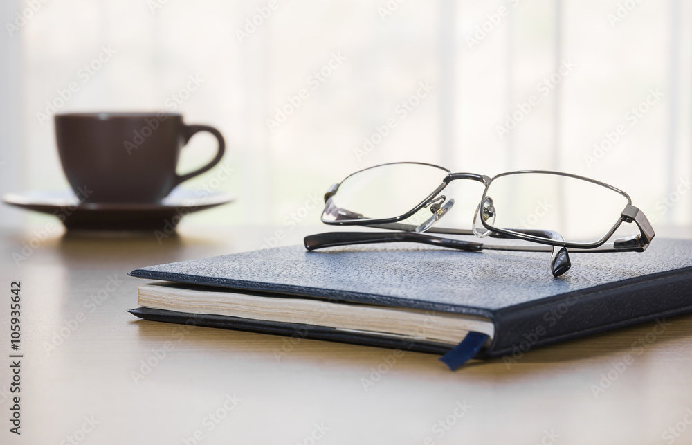 Naklejka premium Glasses and a book on the desk