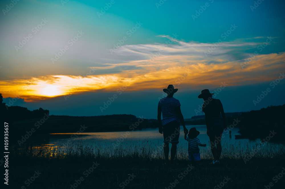 Happy family together, parents with their little child at sunset