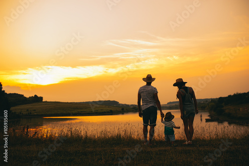 Happy family together, parents with their little child at sunset © jul14ka