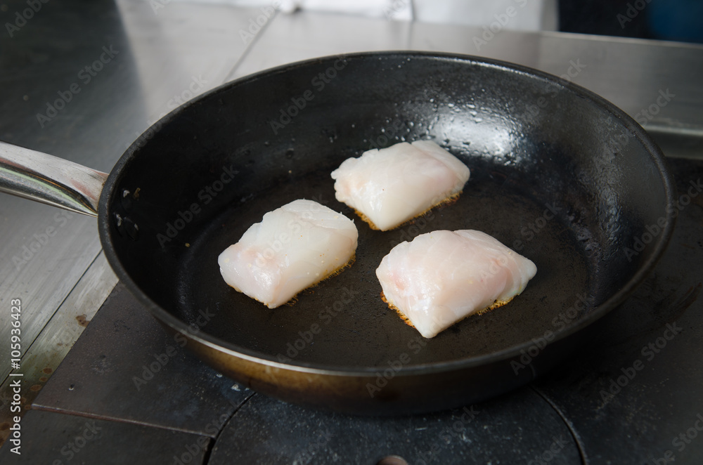 Pan fried golden fish fillet cubes, frying in real butter, in a non stick rustic pan. Pan fried golden fish fillet cubes, frying in real butter, in a non stick rustic pan.