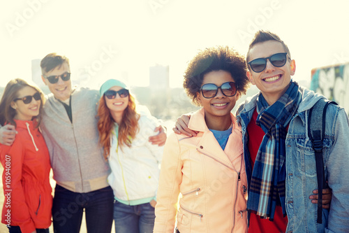 happy teenage friends in shades talking on street