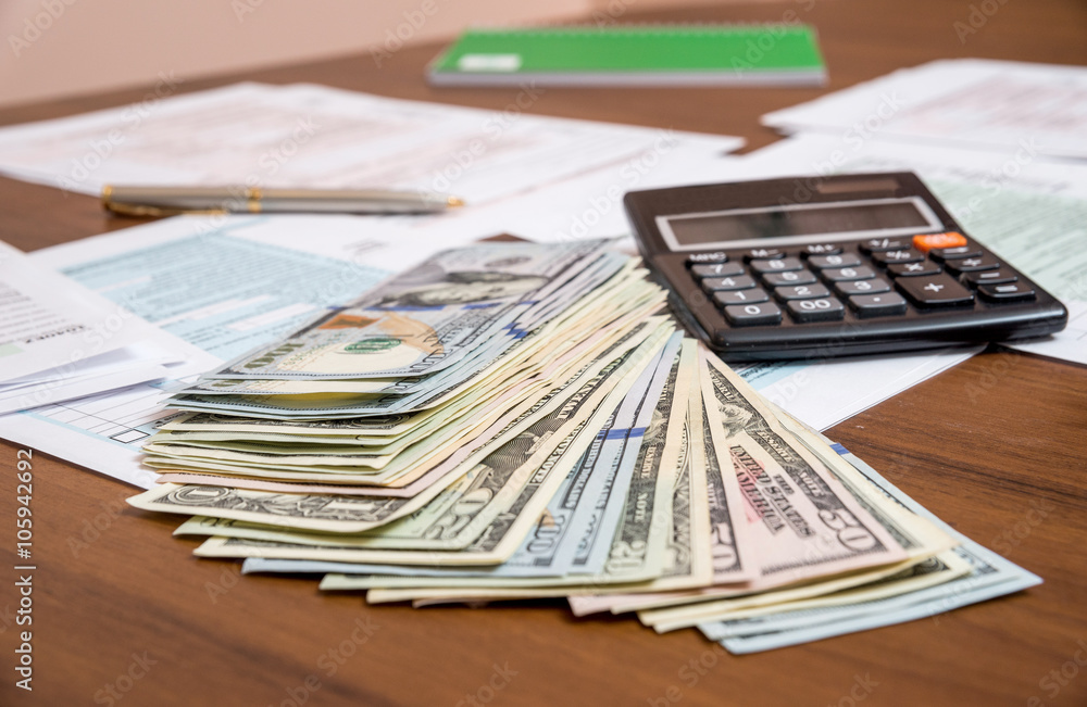 us tax form with dollar and calculator on desk us tax form with dollar and calculator on desk