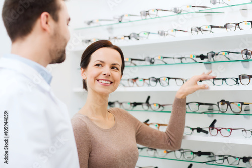 woman showing glasses to optician at optics store