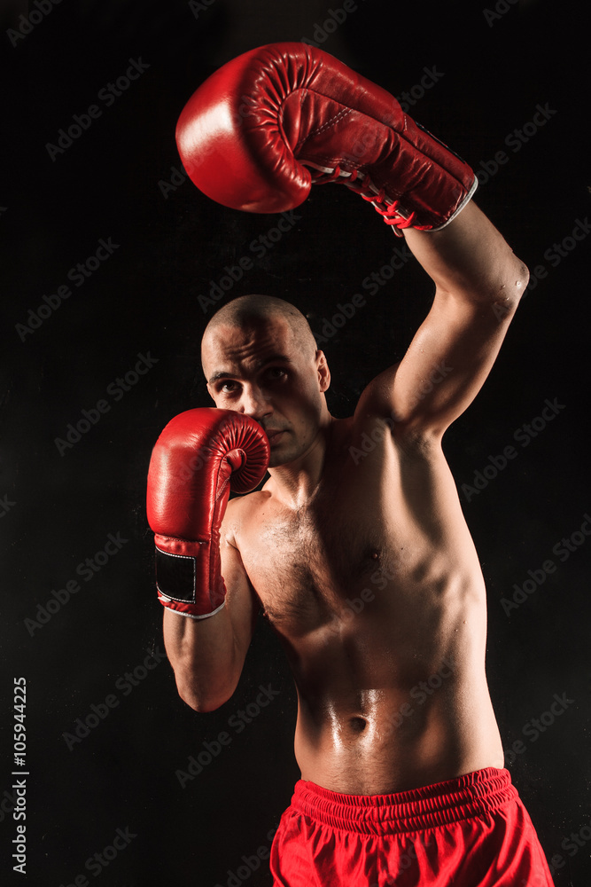 The young man kickboxing on black