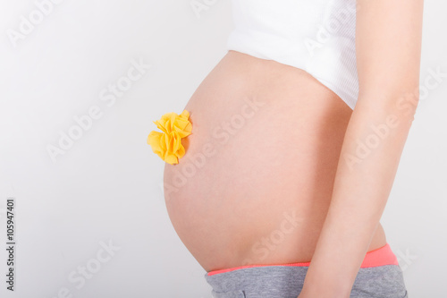 Young pregnant woman / teenager in white cloth with a gift yellow bow waiting for a baby photo