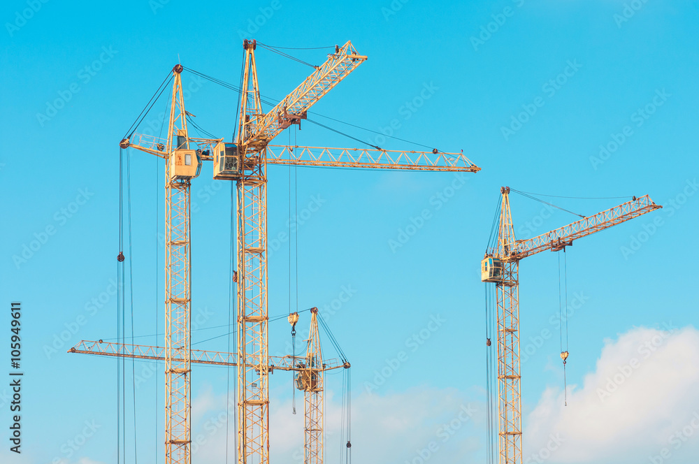 Construction site with cranes against blue sky Construction site with cranes against blue sky
