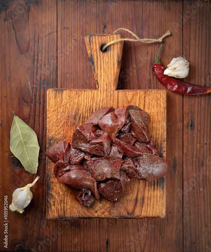 raw liver slices on a cutting board, garlic, pepper and bay leaf 