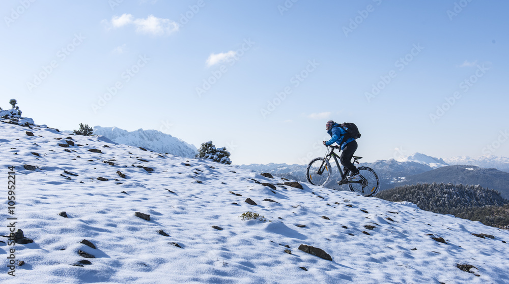 Obraz premium yokuş yukarı karlı dağlarda bisiklet sürmek