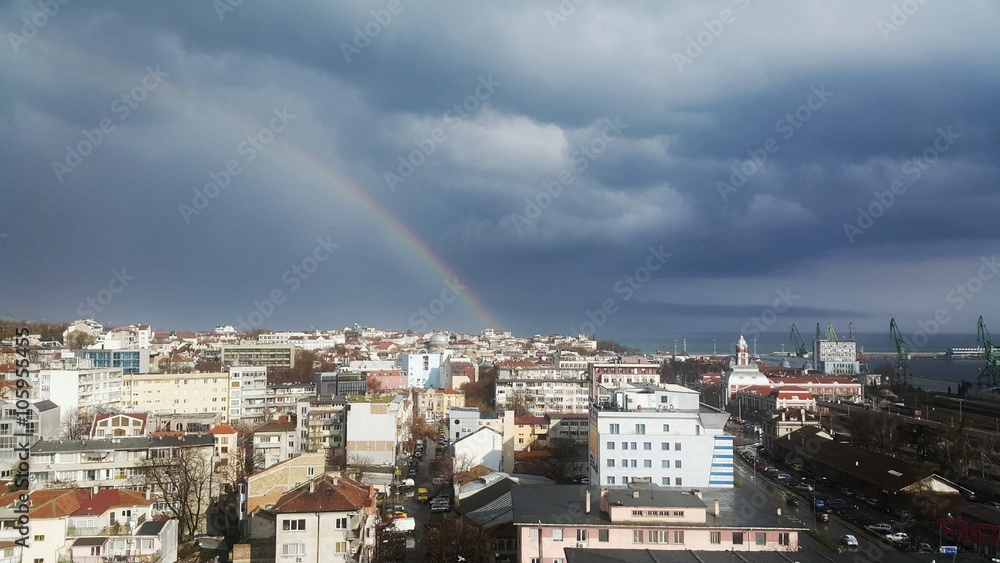 Rainbow above the city and the sea harbour