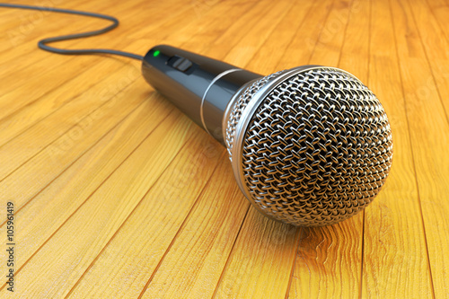 Karaoke party, public speaking and audience communication concept, closeup view of microphone on wooden stage