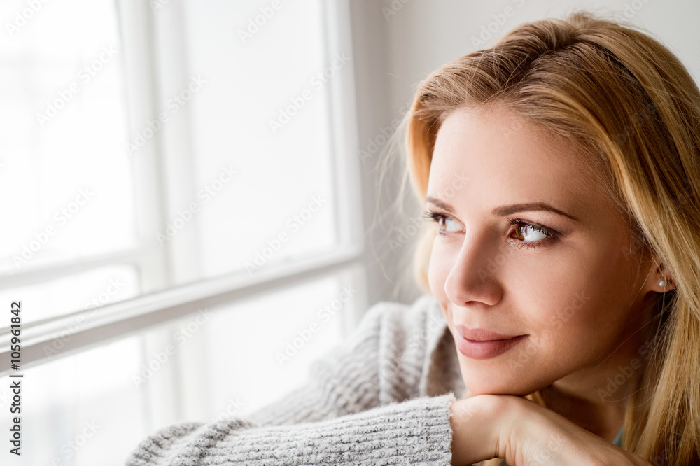 Woman sitting on window sill, looking out of window Woman sitting on window sill, looking out of window