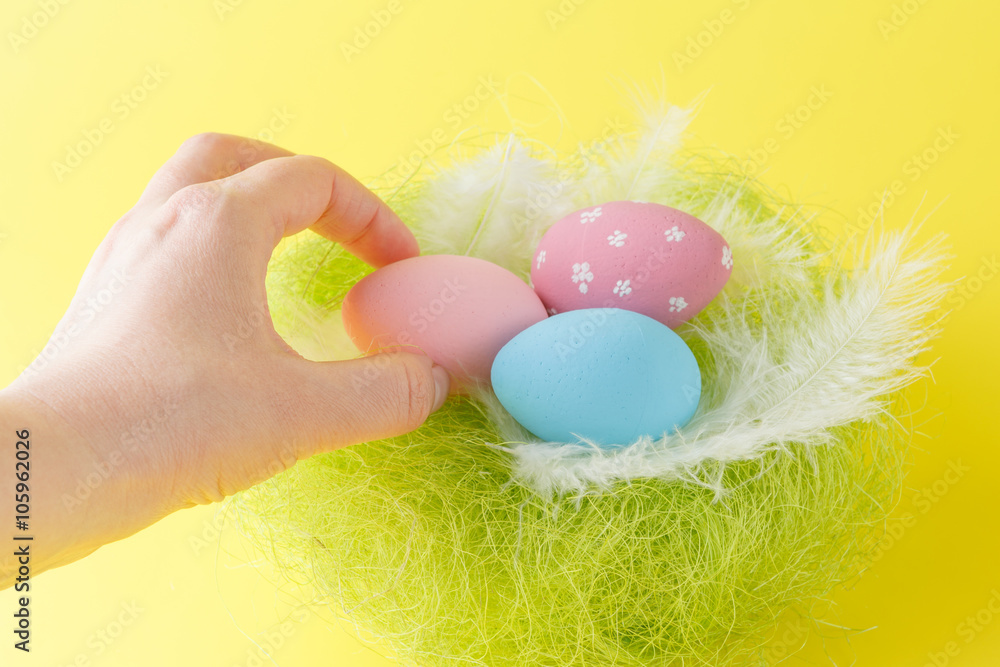 Fototapeta premium Hands holding modern painted easter egg in a small nest