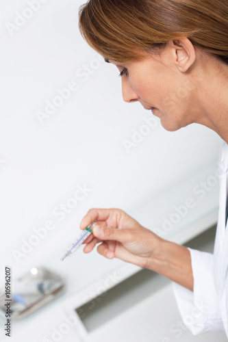 femme médecin regardant un thermomètre 