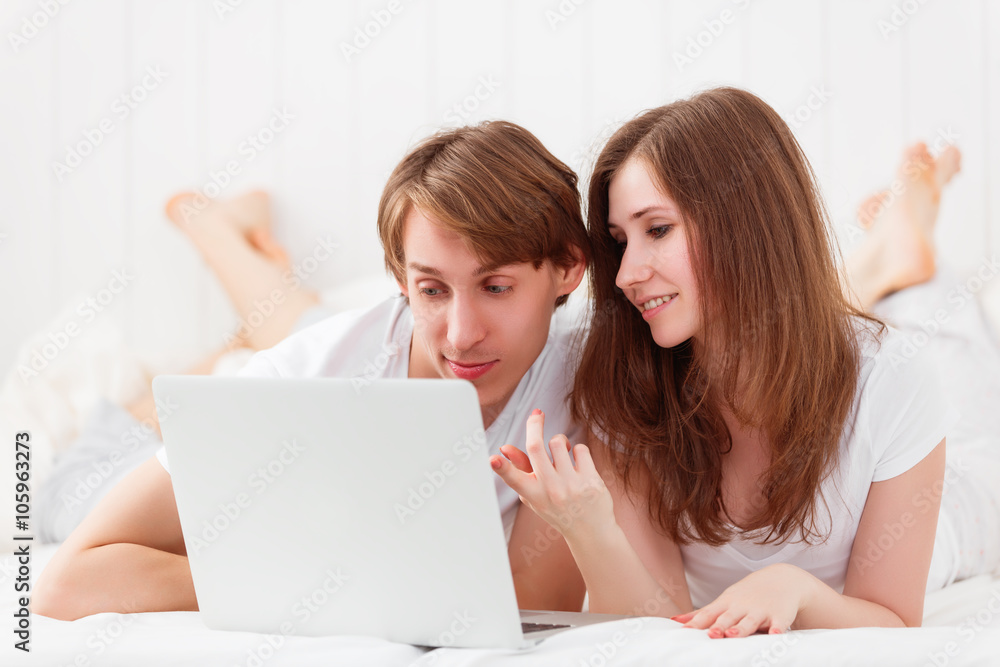 happy couple with laptop on internet in bed happy couple with laptop on internet in bed