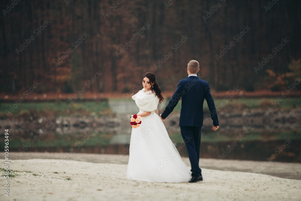 Love and passion - kiss of married young wedding couple near lake Love and passion - kiss of married young wedding couple near lake