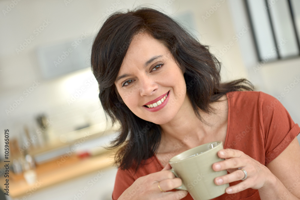 Smiling mature woman at home drinking tea
