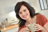 Smiling mature woman at home drinking tea