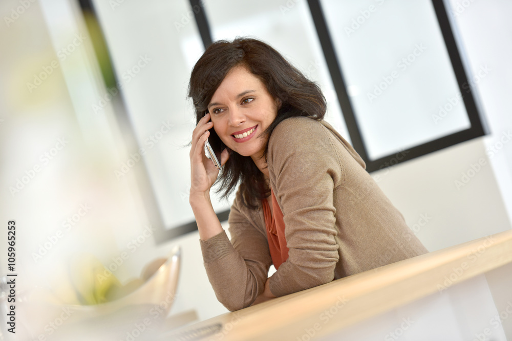 Middle-aged woman in kitchen talking on phone