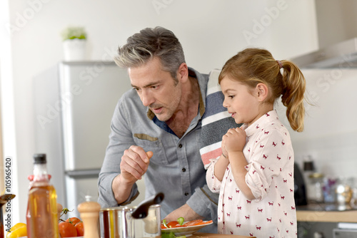 Father with little girl cooking together in kitchen