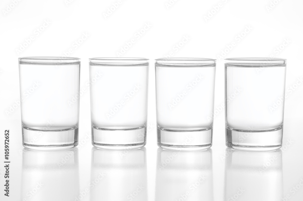 Few small shot glasses filled with alcohol on a light background Few small shot glasses filled with alcohol on a light background