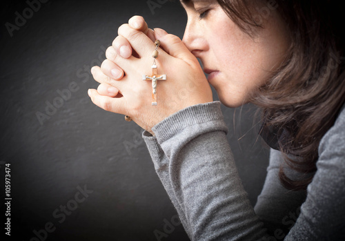 woman meditatin with rosary over dark background