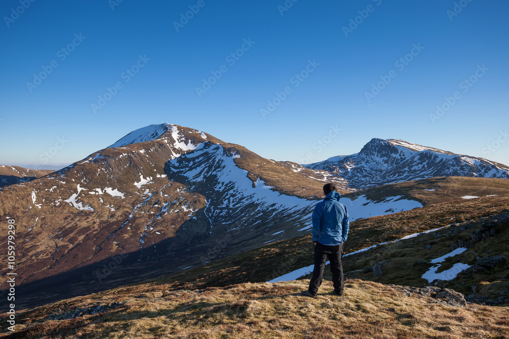 A hiker looking at the mountains in Scottish Highlands.