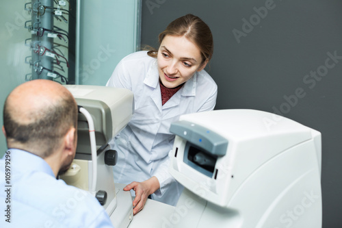 Female optician doing eye examination with aid of slit lamp