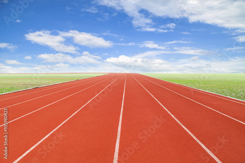 Running track with green grass and blue sky white cloud.